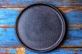 Empty rustic black plate over wooden blue background