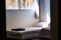 Empty rustic room of cheap hotel apartments with bed white sheet and morning sun light ray through window