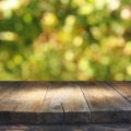 Empty rustic table in front of green spring abstract bokeh background. product display and picnic concept.