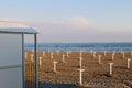 Empty sand beach. Parasol stands and beach changing room waiting for summer with clear blue sky and sea at the background. Royalty Free Stock Photo