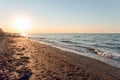 Empty sandy beach with footprints. Evening sea landscape with low sun on horizon. Royalty Free Stock Photo