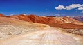 Empty sandy white dirt road into dry arid barren desert valley with red sandstone mountains - Copiapo, Atacama, Chile