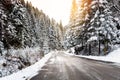 Icy Road through a Snowy Forest in the Mountains Warmly Lit by a Setting Sun in Winter Royalty Free Stock Photo