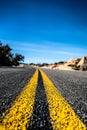 Empty scenic long straight desert road with yellow marking lines. California