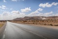 The empty scenic road in the middle of desert, surrounded by dusty hills, in the Middle East Royalty Free Stock Photo