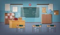 Empty school classroom with green chalkboard, pendant lights, various educational materials, desks, chairs and other