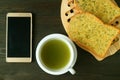 Empty Screen Smartphone with a cup of Hot Green Tea and Garlic Butter Toasts on Dark Color Background Royalty Free Stock Photo
