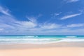 Empty sea with white sand, undulating waves cover the beach on a sunny day. Overlooking the horizon and the clouds with blue sky.