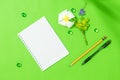 Empty sheet of notepad with pen, pencil and frangipani flower on green background for some idea or message