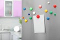 Empty sheet of paper with colorful magnets on refrigerator door in kitchen Royalty Free Stock Photo