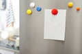 Empty sheet of paper with colorful magnets on refrigerator door in kitchen Royalty Free Stock Photo