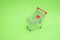 Empty shooping trolley cart on green background Royalty Free Stock Photo