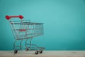 Empty shopping cart on wooden table with green backround. Consumerism concept. Online shopping concept. Royalty Free Stock Photo