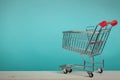 Empty shopping cart on wooden table with green backround. Consumerism concept. Online shopping concept. Royalty Free Stock Photo