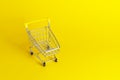 Empty shopping cart with yellow handle on cheerful yellow background. Shopping concept