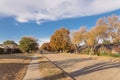 Empty sidewalk and quite neighborhood street with row of suburban house and colorful fall foliage in Texas, USA