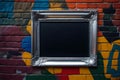 An empty silver photo frame hanging on a colorful, graffiti-covered brick wall in an urban setting