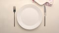 Empty simple white ceramic plate with silverware on white table Royalty Free Stock Photo