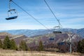 Empty ski lift above a rocky hillside landscape with rocky peaks in the distance Royalty Free Stock Photo