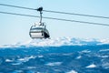 Empty ski lift on a cable with snow covered mountains in the background Royalty Free Stock Photo