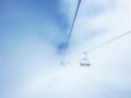 an empty ski lift of a ski resort in the fog, a chairlift gets lost in the dense fog in a winter resort Royalty Free Stock Photo