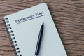 Empty small notepad with pen and handwriting headline as Retirement Plan on wood table in soft vintage tone, planning for saving Royalty Free Stock Photo