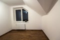 Empty small room with wooden oak parquet floor, newly painted white walls, heating radiator and a window. Attic room Royalty Free Stock Photo