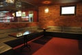 Empty smoking room of a restaurant designed in red color brick walls, couches and wooden tables with ashtrays