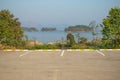 Empty space of car parking lot with green bush and lake in the background. Royalty Free Stock Photo