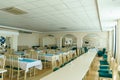 An empty spacious banquet hall with tables and chairs and panoramic windows. Preparing a restaurant for a wedding dinner,