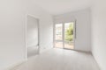 Empty spacious room with light walls and wooden laminate flooring with a large window to the floor and access to another Royalty Free Stock Photo