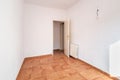 An empty spacious room with old square worn caramel colored floor tiles and a radiator on the wall, with an open door Royalty Free Stock Photo