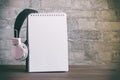 An empty spiral notebook with headphones hanging from the side. Close-up, white brick wall. Ready-made layout for your ad