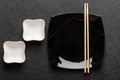 Empty square black plate with chopsticks and two white gravy boats on a dark background. Japanese food style. Top view Royalty Free Stock Photo