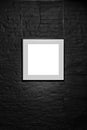 Empty square frame on black brick wall. Blank space poster or art frame waiting to be filled. Square Black Frame Mock-Up Royalty Free Stock Photo