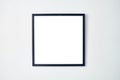 An empty square photo frame with a black border hanging on a white wall Royalty Free Stock Photo