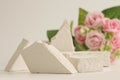Empty stack of stones platform podium and rose flower bouquet on beige background. Minimal empty display product presentation