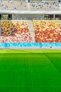 Empty stadium with colored chairs in tribune and the green lawn grass Royalty Free Stock Photo