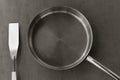 Empty stainless steel frying pan and spatula overhead view on the gray background, black white photos Royalty Free Stock Photo