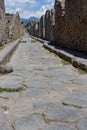 Empty stone street with ruins in Pompeii, Italy. Antique road in italian ancient town against mountain. Abandoned street. Royalty Free Stock Photo