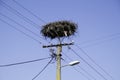 Empty stork nest at the top of an electrical tower on blue sky background Royalty Free Stock Photo