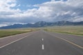Empty straight asphalt road at grassland. Mountain and white clouds Royalty Free Stock Photo