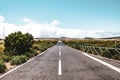 Empty straight road surrounded by dry landscape. Pespective from the middle of the road, standing on the middle line. Empty