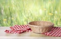 Empty straw basket decorated with checkered kitchen towel on table with green natural background.Easter display Royalty Free Stock Photo