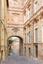 Empty street with red bricks building and arch in a summer day in Mondovi, Italy
