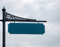 Empty street sign on metal post, cloudy sky in the background.