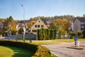 Empty street with small houses and green bushes and road signs in the fall