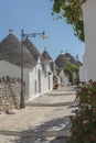 Empty street with typical white houses and cone-shaped roofs in Alberobello, Italy