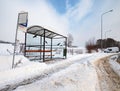 Empty suburban bus stop covered with snow in winter. Slipery pavement