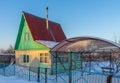 Empty suburban plot covered with snow and left for the winter brick cottage house on wintery evening at sunset. Russian dacha